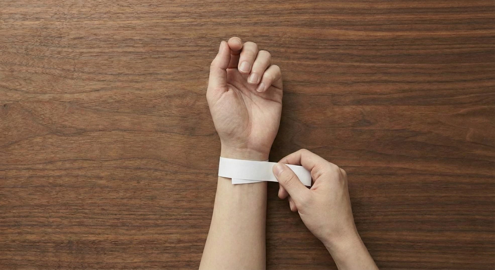 Plain white strip of paper being wrapped around the wrist as a tape measure substitute. Plain white strip of paper being wrapped around the wrist as a tape measure substitute.